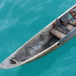 A wooden canoe on clear turquoise water, seen from above