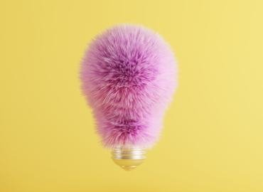 A pink feathery light bulb on a yellow background