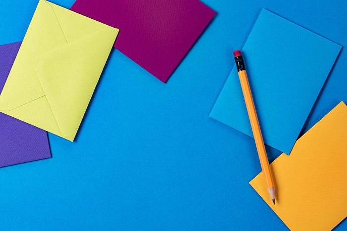 Coloured paper and a pencil on a blue background