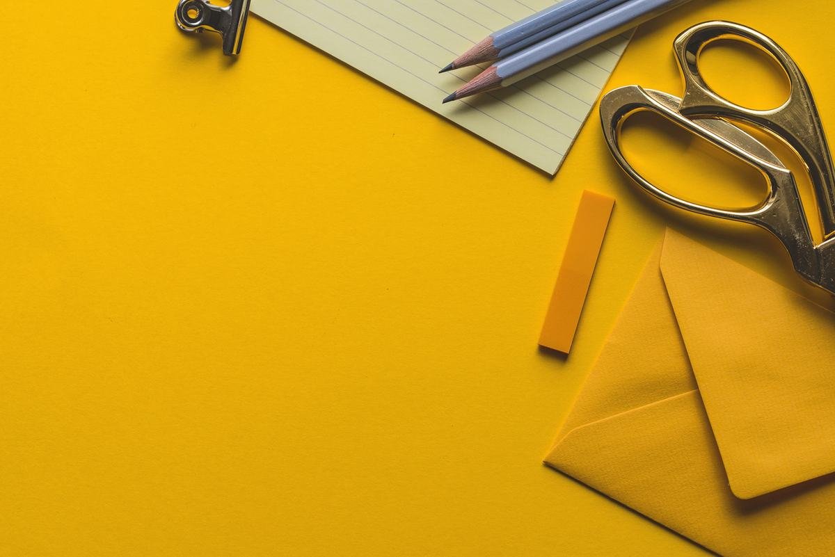 Scissors, pencils and envelopes on a yellow desk